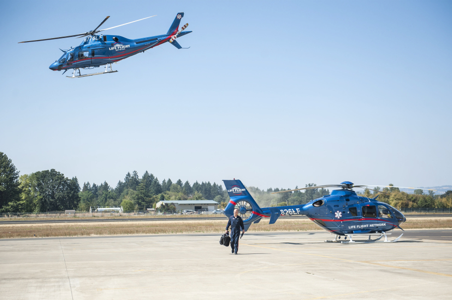 Pilot Jeff Kotson walks away from his helicopter while a second aircraft takes off to respond to a call at Life Flight Network’s Aurora, Ore., base.