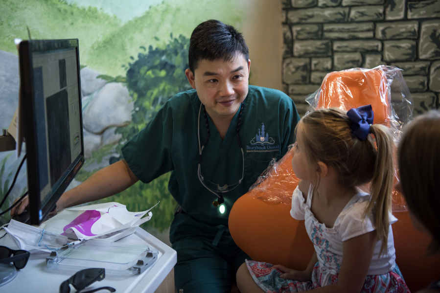 Dr. Ron Hsu looks over X-rays with patient Taryn Hatfield of Washougal, 6, center, and Taryn’s mom, Leah, at Storybook Dental in Camas. Hsu is working on a countywide program to help educate local schools on how to treat dental trauma and tooth avulsions.