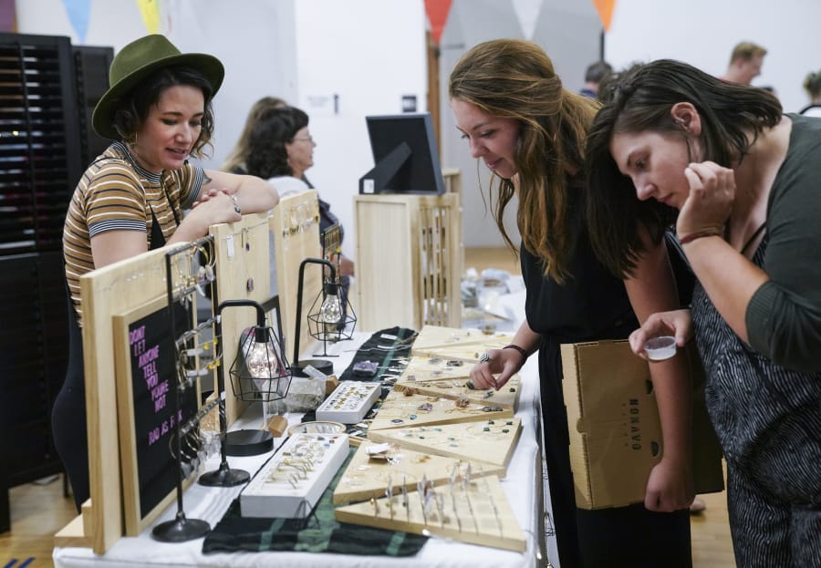 Kirsten Elise, left, a raw gemstone jewelry artist from Portland, helps customers Chantal Krystiniak, of Vancouver, and Elizabeth Meier, of Puyallup, pick out jewelry at Night Market Vancouver in 2018.