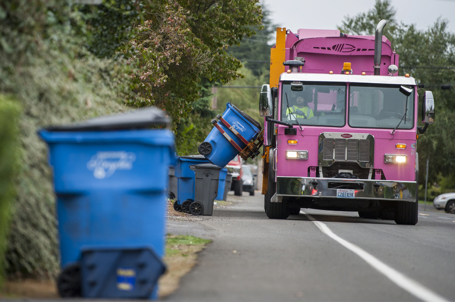 A Waste Connections driver collects curbside recycling bins from a Vancouver neighborhood.
