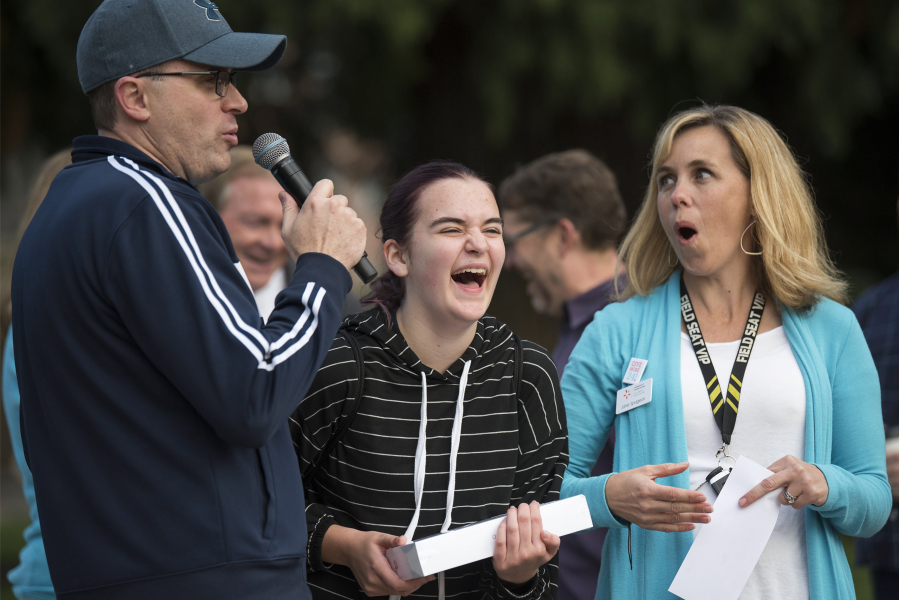 Jim Mains, with High Five Media, from left, Ava Bonner of Camas and Janie Spurgeon, vice president of development for the Community Foundation for Southwest Washington, react to Bonner’s victory in a game of Simon Says, which won her an iPad and $250 to her charity, Camas Christian Academy, during a kickoff event at Ester Short Park for Give More 24! on Thursday morning.