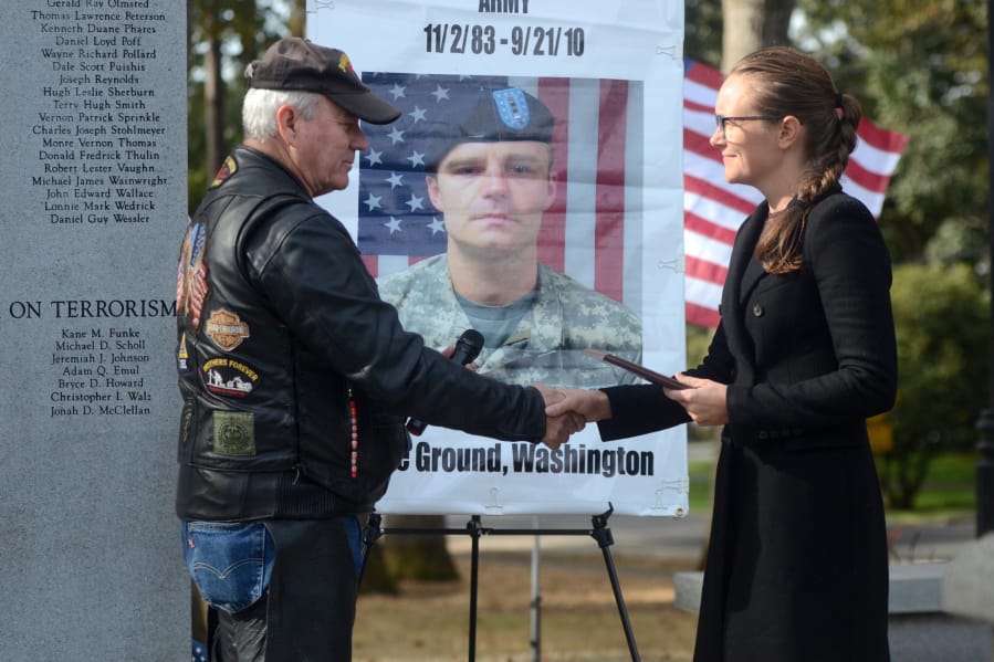 Lynn Vaughn, left, district captain of the Southwest Washington chapter of the Patriot Guard Riders, hands Nina Wilson, widow of Army Chief Warrant Officer 2 Jonah McClellan, a plaque honoring McClellan, who died eight years ago Friday in Afghanistan.
