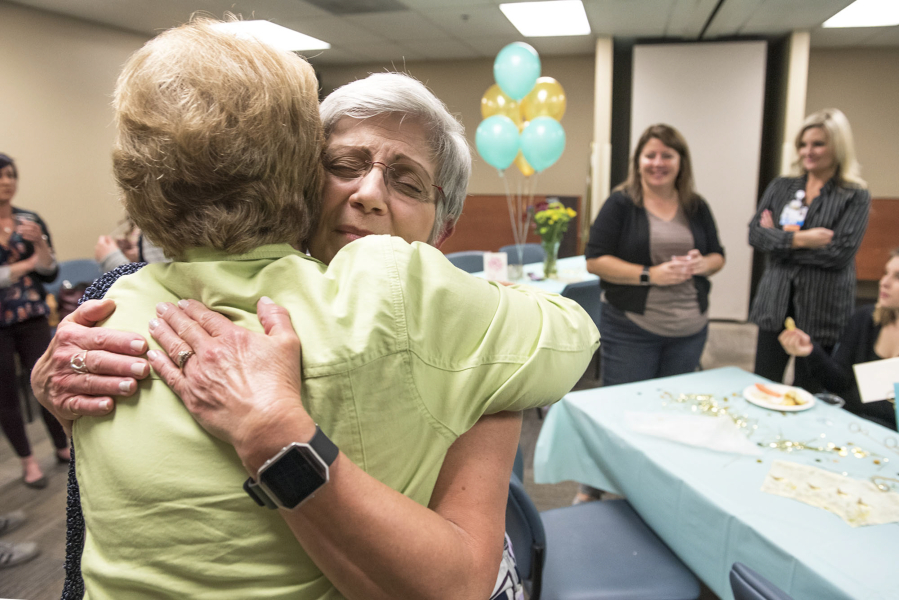 Kathi Anderson, left, hugs Lorreta Holcomb on Friday during an event celebrating Holcomb’s 50 years working for some variation of PeaceHealth Southwest Medical Center in Vancouver. The two women met in high school and worked together for more than 20 years.