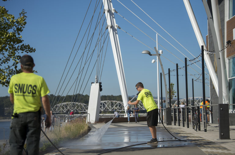 Kory Snuggerud of Snugs Services pressure-washes the sidewalk outside the WildFin American Grill while helping to prepare for the grand opening of The Vancouver Waterfront on Friday morning, Sept. 28, 2018.