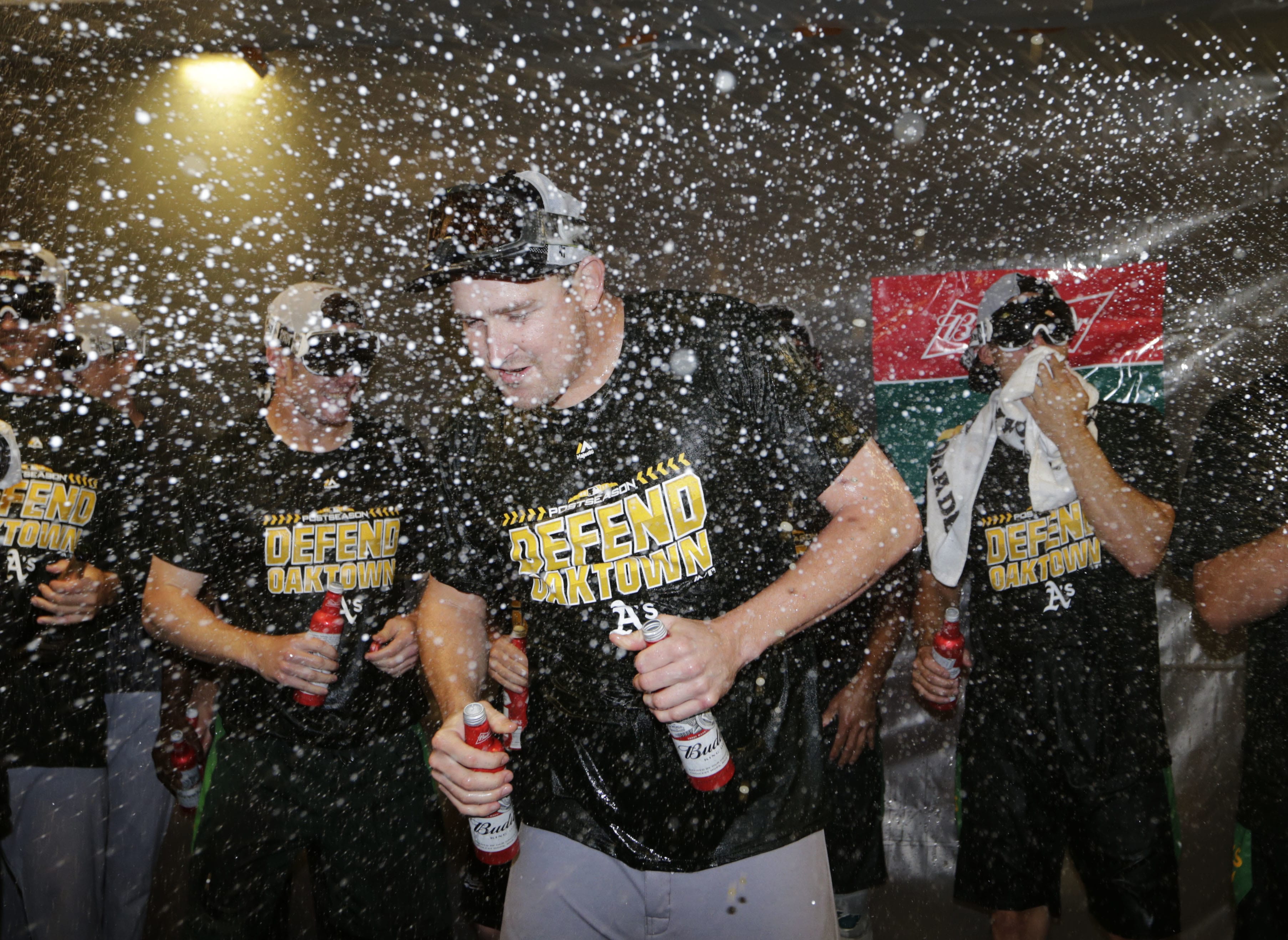 Oakland Athletics' Trevor Cahill is doused in the clubhouse celebration after clinching a wild card spot after the baseball game against the Seattle Mariners, Monday, Sept. 24, 2018, in Seattle.