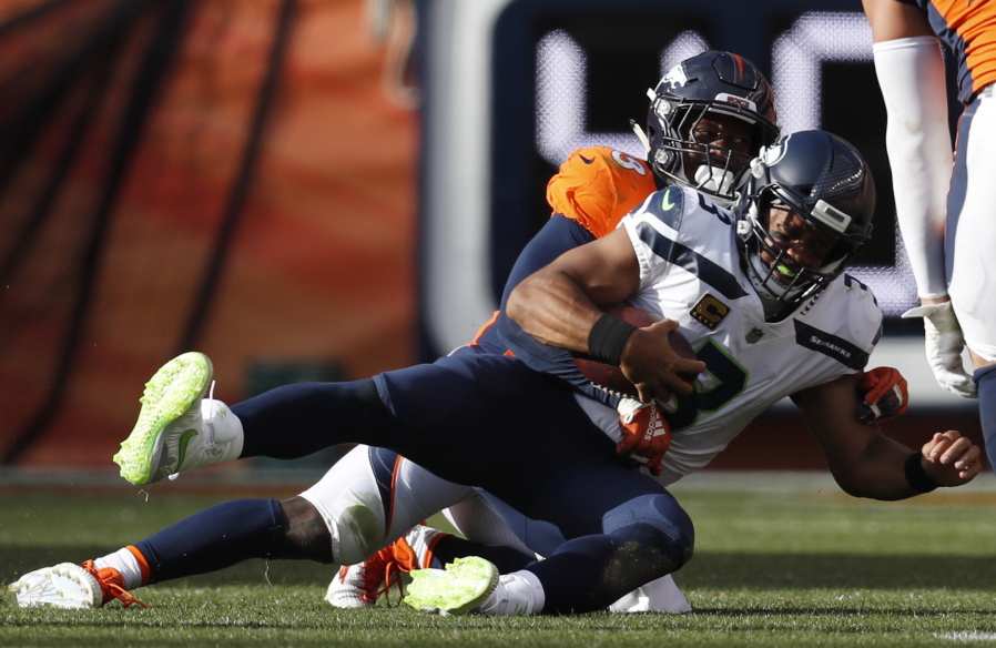 Denver Broncos linebacker Von Miller, behind, hauls down Seattle Seahawks quarterback Russell Wilson (3) for a sack during the second half of an NFL football game Sunday, Sept. 9, 2018, in Denver.