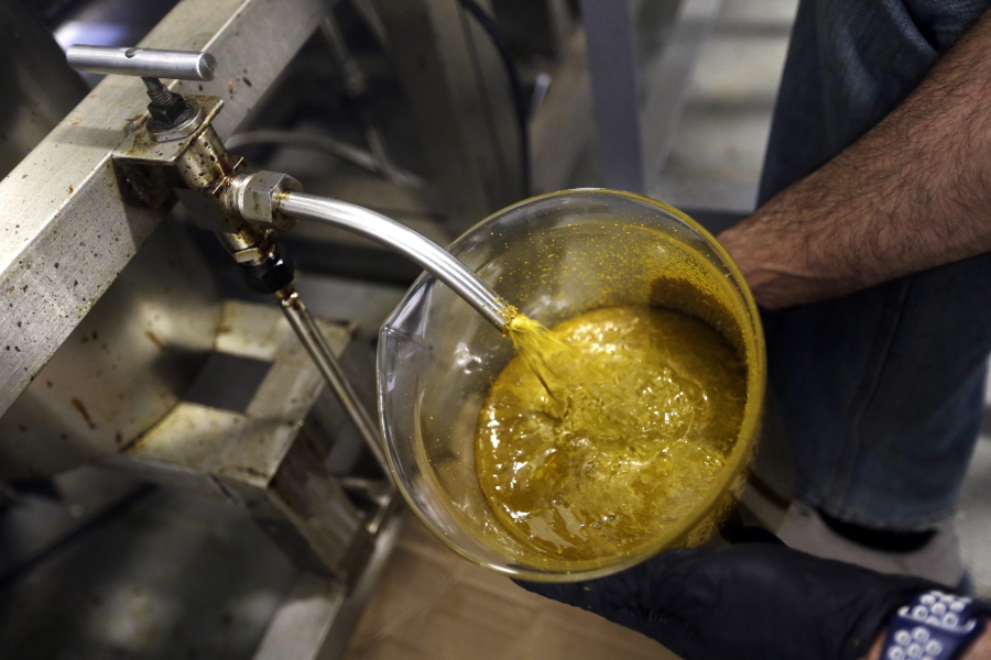 FILE--In this April 24, 2018, file photo, the first rendering from hemp plants extracted from a super critical CO2 extraction device on its’ way to becoming fully refined CBD oil spurts into a large beaker at New Earth Biosciences in Salem, Ore. The Coca-Cola Company says that it’s “closely watching” the growth of the use of a non-psychoactive element of cannabis in wellness drinks.