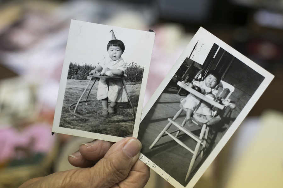 In this Aug. 17, 2018 photo, Yoshiko Hide, holds family photos on the Toppenish family farm of herself at 7-month-olds at the Yakima Valley Museum in Yakima, Was. Japanese immigrants and Yakama Nation citizens go back decades, to the earliest years that immigrants came to the Valley to help clear the land, dig irrigation canals and work in agriculture. The Yakama Reservation offered a unique opportunity for the immigrants to lease land because as a sovereign nation, it was not subject to the anti-Chinese and anti-Japanese laws implemented by the state.