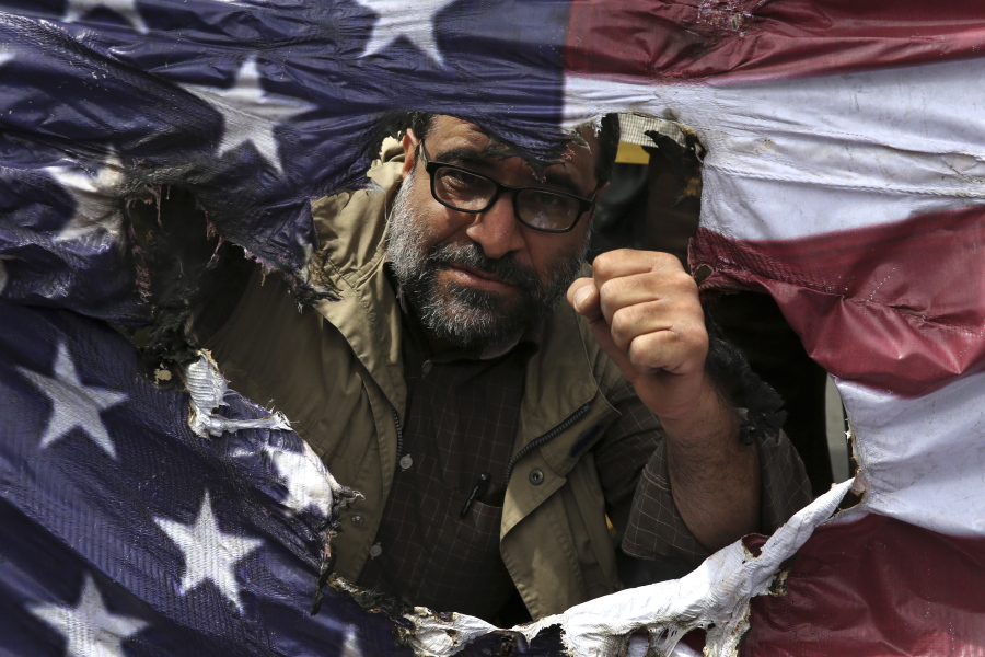 An Iranian protestor clenches his fist behind a burnt representation of the U.S. flag during a protest over U.S. President Donald Trump’s decision to pull out of the nuclear deal with world powers, in Tehran, Iran. Ahead of the 40th anniversary of Iran’s Islamic Revolution, the country’s government is allowing more criticism to bubble up to the surface. But limits still clearly exist in Iran’s Shiite theocracy and the frustration people feel may not be satiated by complaining alone.