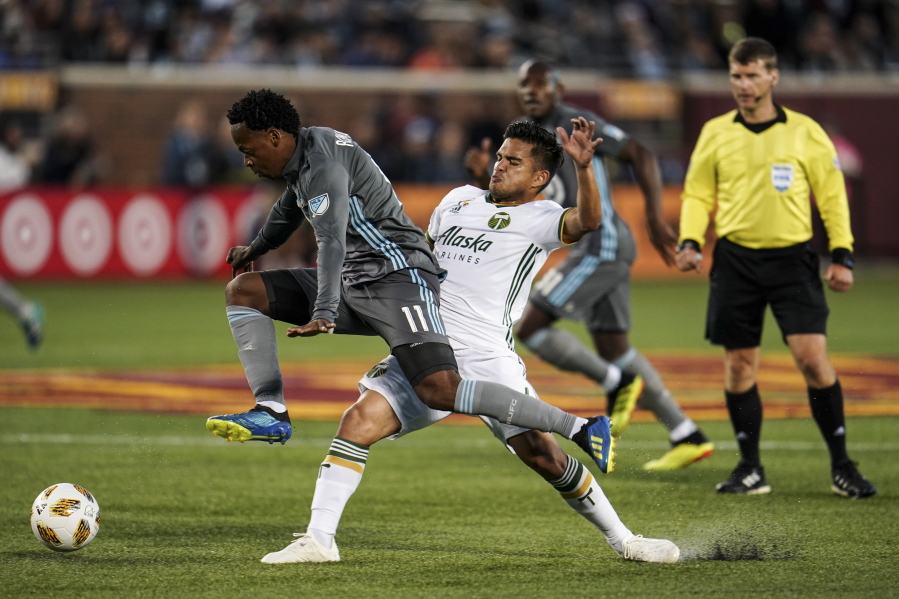 Minnesota United midfielder Romario Ibarra leaps into air while chasing the ball under the defense of Portland Timbers midfielder Andres Flores (14) during the first half of an MLS soccer match Saturday, Sept. 22, 2018, in Minneapolis.