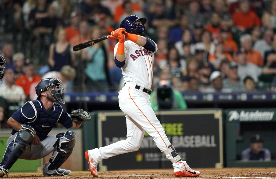 Houston Astros’ Marwin Gonzalez, right, hits a two-run home run as Seattle Mariners catcher Chris Herrmann watches during the third inning of a baseball game Tuesday, Sept. 18, 2018, in Houston. (AP Photo/David J.