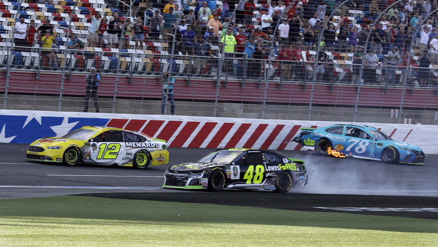 Ryan Blaney (12) drives past the wrecked cars of Jimmie Johnson (48) and Martin Truex Jr. (78) to win the NASCAR Cup series auto race at Charlotte Motor Speedway in Concord, N.C., Sunday, Sept. 30, 2018.