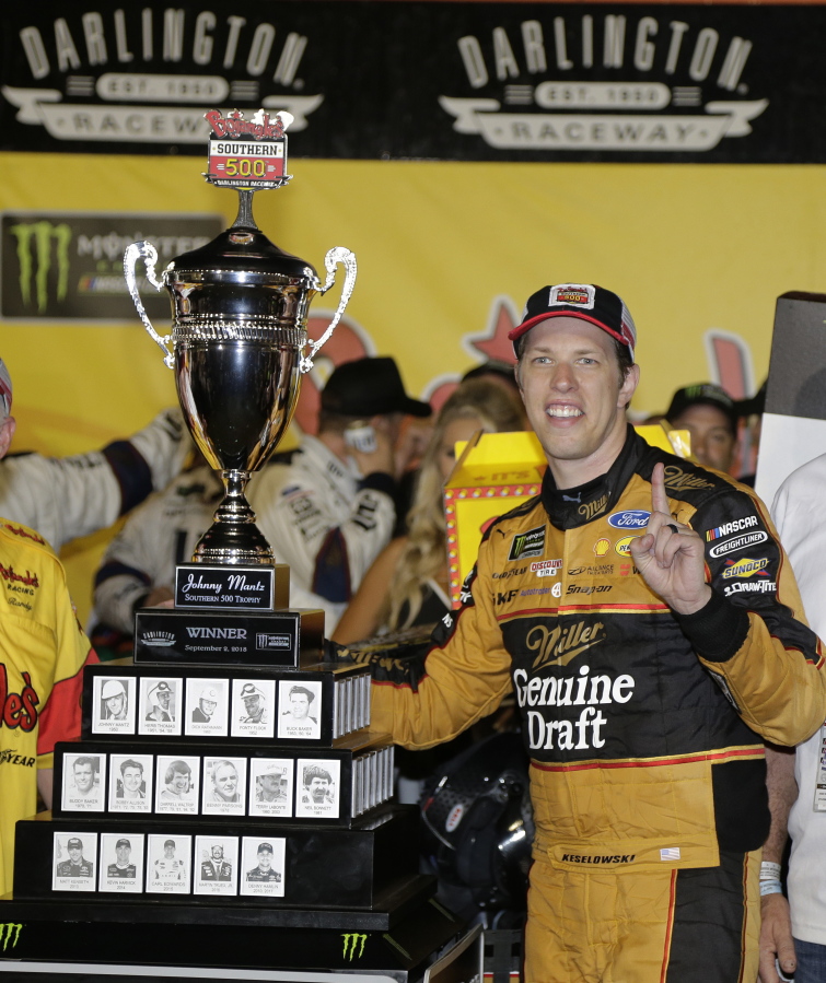 Brad Keselowski stands by his trophy after winning the NASCAR Cup Series auto race at Darlington Raceway, Sunday, Sept. 2, 2018, in Darlington, S.C.