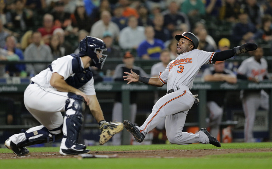 Baltimore Orioles’ Cedric Mullins scores on a ball hit by Jonathan Villar with Seattle Mariners catcher David Freitas waiting for the throw during the seventh inning of a baseball game Tuesday, Sept. 4, 2018, in Seattle.