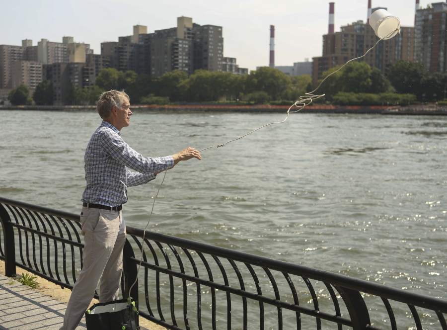 Mark Stoeckle throws a bucket into New York’s East River on Aug. 10. Scientists say scooping a bottle of water or a sample of soil can be enough to detect the genetic material of endangered or elusive species.