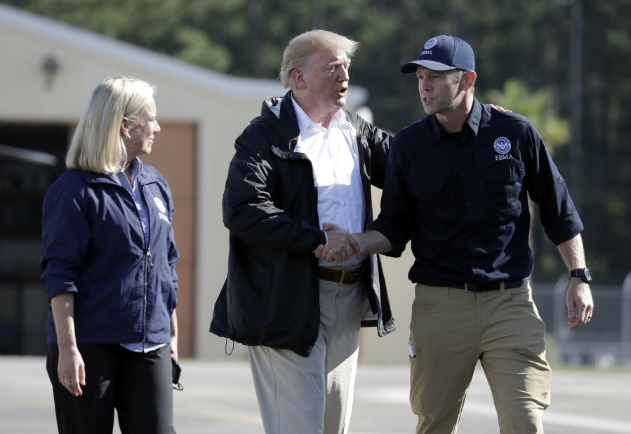 President Donald Trump shakes hands with FEMA Administrator Brock Long as Homeland Security Secretary Kirstjen Nielsen watches after visiting areas in North Carolina and South Carolina impacted by Hurricane Florence, Wednesday, Sept. 19, 2018, at Myrtle Beach International Airport in Myrtle Beach, S.C.