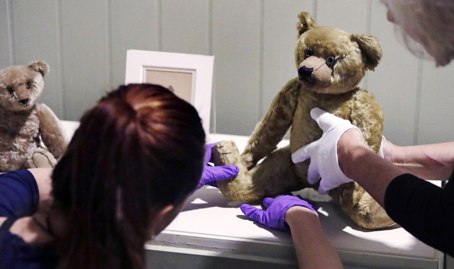 In this Thursday, Sept. 13, 2018 photo, gallery stylists position antique Winnie the Pooh bears while preparing the “Winnie-the-Pooh: Exploring a Classic” exhibit at the Museum of Fine Arts in Boston. The show opening Saturday, Sept. 22, comprises nearly 200 original drawings, letters, photographs and early editions.