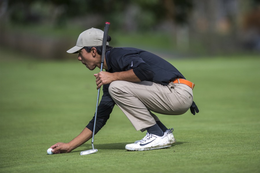 Battle Ground’s Anthony Tobias places his ball before putting during the 4A district boys golf tournament at Tri-Mountain Golf Course on Tuesday.