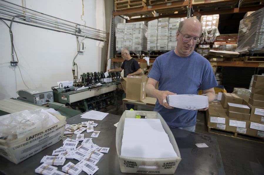 Nathan Stewart, foreground, and Mark Furlong sort election ballots Wednesday as they prepare them to mail to Clark County voters. The county contracts with Send It Direct Mail, a company based in Portland, to get the ballots out.