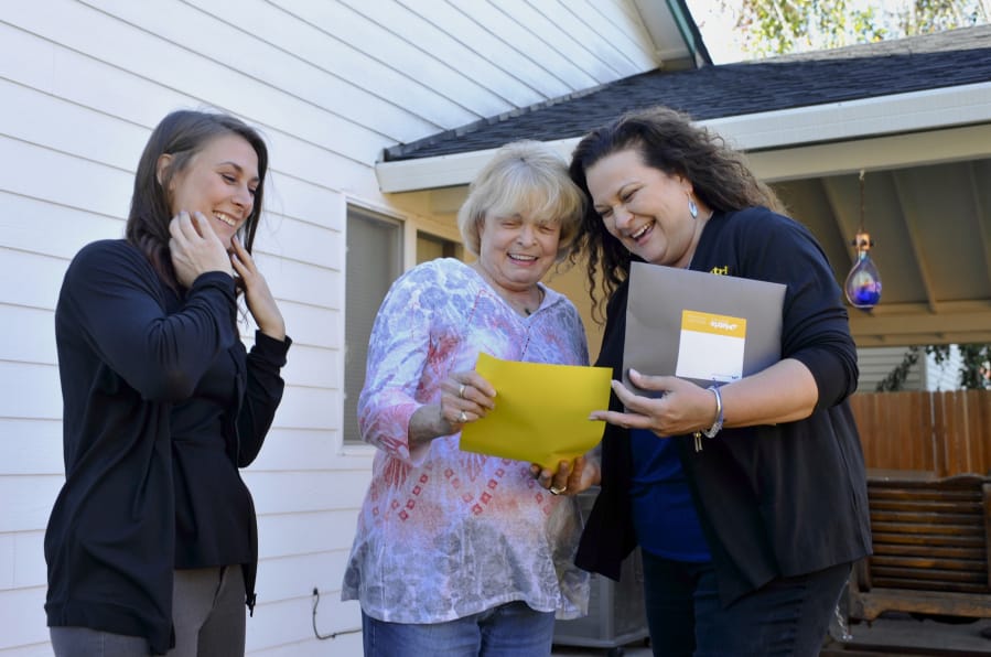 Homeowner Alice Jull of Vanport Rigging, center, receives documents during a follow-up visit from Matrix Roofing CEO Wendy Marvin, right, and her assistant Rhianna Phillips, after the completion of the roofing job on Jull’s home in Salmon Creek earlier this month.