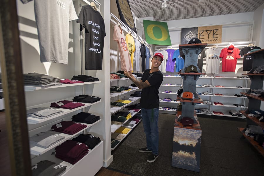Roberto Gonzalez, owner of EYE Clothing Co., greets customers Thursday while working in Vancouver Mall .