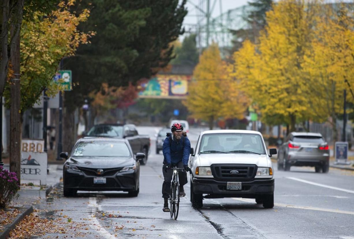 A cyclist navigates through traffic on Columbia Street near the intersection with West Sixth Street, while at left in the background a car blocks the bike lane. Via the Westside Bike Mobility Project, the city is designing north-south bike routes to enable riders of varying abilities to ride between downtown Vancouver and the city’s other west-side neighborhoods.