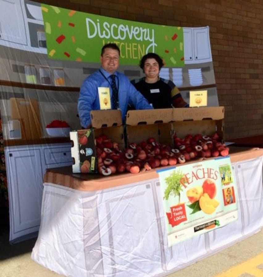 Fircrest: Jodee Nickel, Washington State University Extension’s Supplemental Nutrition Assistance Program Education educator, left, and Chad Kirby of Chartwells Food Service at Fircrest Elementary School for the Harvest of the Month program.