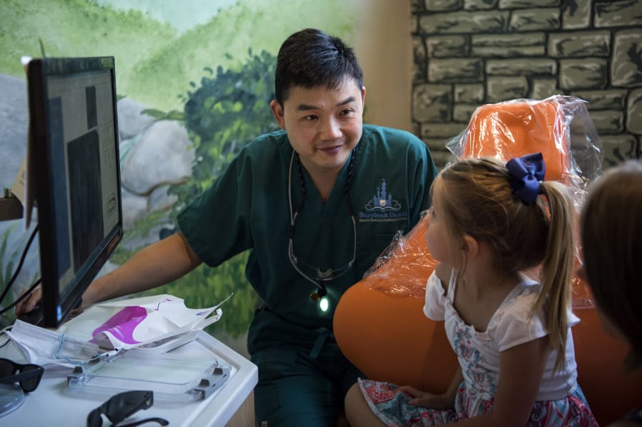Dr. Ron Hsu looks over X-rays with patient Taryn Hatfield of Washougal, 6, center, and Taryn’s mom Leah, at his practice Storybook Dental in Camas in September.