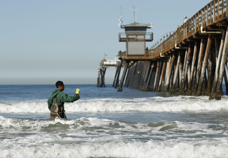 Mar Vista High School sophomore Anthony Gass collects a water sample at the Imperial Beach Pier on Thursday. The school and the Surfrider Foundation have teamed up to monitor water pollution north of Tijuana. K.C.