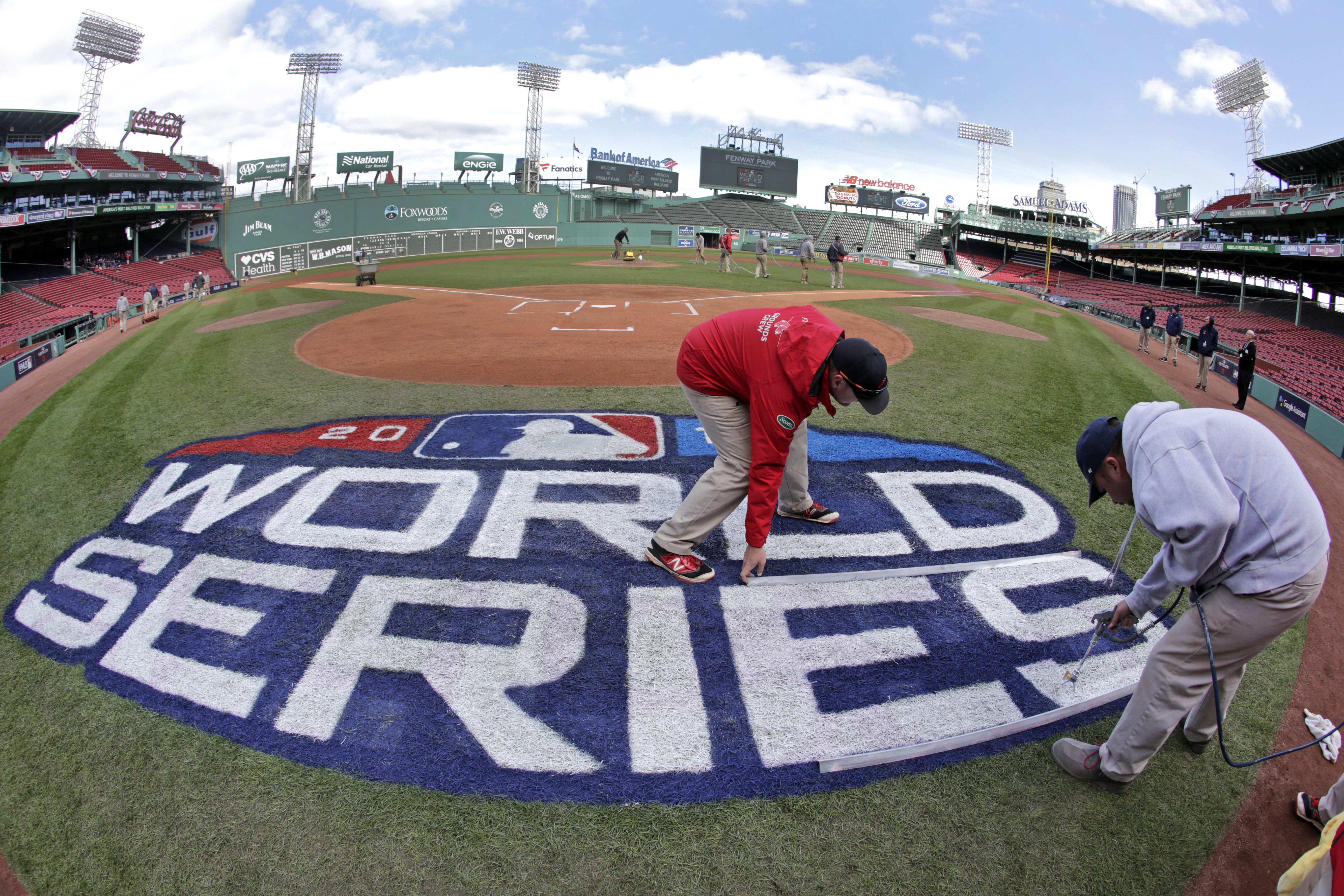 Grounds crew members paint the World Series logo behind home plate at Fenway Park, Sunday, Oct. 21, 2018, in Boston as they prepare for Game 1 of the baseball World Series between the Boston Red Sox and the Los Angeles Dodgers scheduled for Tuesday.