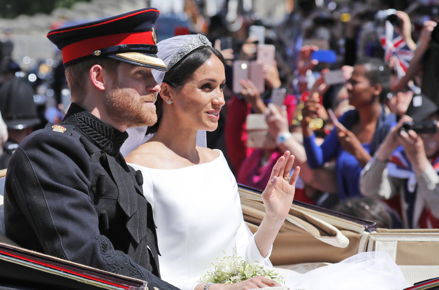 FILE - In this file photo dated Saturday, May 19, 2018, Britain’s Prince Harry and his bride Meghan Markle, ride in a carriage after their wedding ceremony at St. George’s Chapel in Windsor Castle in Windsor, near London, England. Kensington Palace announced Monday Oct. 15, 2018, that Prince Harry and his wife the Duchess of Sussex are expecting a child in spring 2019.