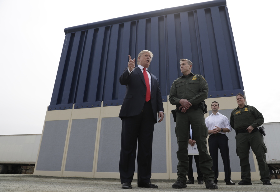 FILE - In this March 13, 2018, file photo, President Donald Trump speaks during as he reviews border wall prototypes, in San Diego, as Rodney Scott, the Border Patrol's San Diego sector chief, listens. Congress is heading toward a post-election showdown over President Donald Trump’s border wall, as GOP leaders signal they’re willing to engage in hardball tactics that could spark a partial government shutdown and the president revs up midterm crowds for the wall, a centerpiece of his 2016 campaign and a top White House priority.