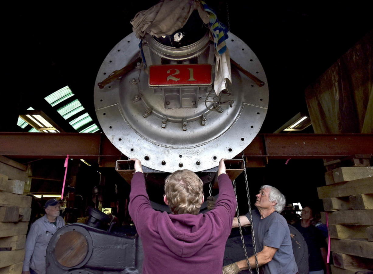 In this Sept. 19, 2018, photo, Ryder Dopp, center, and other volunteers help steer a part of the No. 21 Baldwin locomotive into place in Astoria, Ore. The Astoria Railroad Preservation Association is the third group attempting to revive the 93-year-old locomotive, originally used to haul crops and petroleum along the Santa Maria Valley Railroad in Southern California.