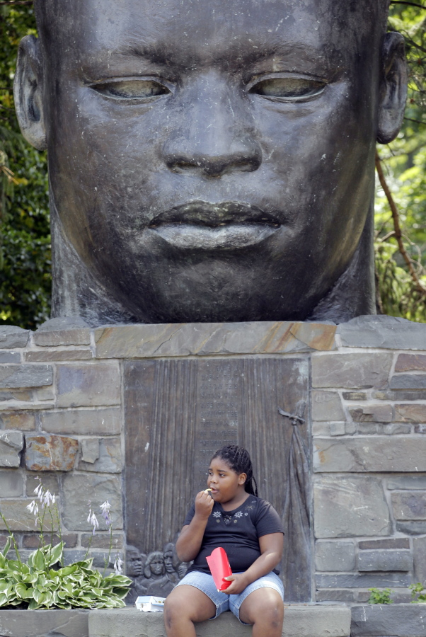 Tonae Johnson eats her lunch in the park in front of a Martin Luther King Jr. statue during the warm summer weather in Buffalo, N.Y. A community activist says he has gathered more than 6,000 signatures to replace the sculpture of the civil rights leader. Samuel Herbert says his goal is to get 10,000 signatures and a new statue by 2020. He says the 8-foot bust of King that sits in a namesake park in Buffalo doesn’t look like the civil rights leader.