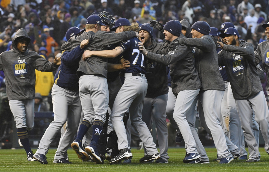 Milwaukee Brewers celebrate after the final out by the Colorado Rockies in the ninth inning of Game 3 of a baseball National League Division Series Sunday, Oct. 7, 2018, in Denver. The Brewers won 6-0 to sweep the series in three games and move on to the National League Championship Series.