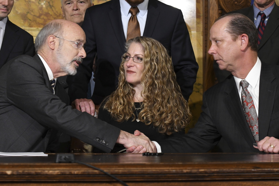 Pennsylvania Gov. Tom Wolf of Pennsylvania shakes hands with Jim Piazza after signing anti-hazing legislation inspired by Piazza’s son, Penn State student Tim Piazza who died after a night of drinking in a fraternity house, Friday, Oct. 19, 2018 in Harrisburg, Pa. Sitting between them is Evelyn Piazza, the mother of Tim Piazza.
