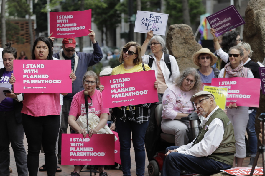 FILE - In this July 10, 2018 file photo, protesters hold signs supporting Planned Parenthood in Seattle, as they demonstrate against President Donald Trump and his choice of federal appeals Judge Brett Kavanaugh as his second nominee to the Supreme Court. On Wednesday, Oct. 10 Planned Parenthood unveiled a plan to protect access to abortion as widely as possible even if the Supreme Court moves to curtail women’s right to undergo the procedure. (AP Photo/Ted S.