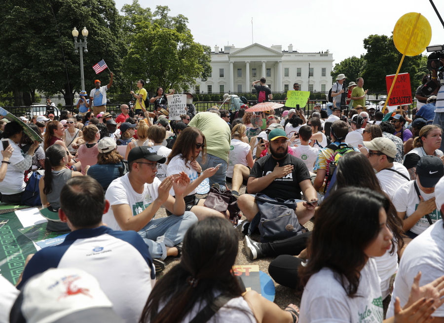 FILE - In this April 29, 2017, file photo, demonstrators sit on the ground along Pennsylvania Ave. in front of the White House in Washington. The National Park Service is exploring the question of whether it should recoup from protest organizers the cost of providing law enforcement and other support services for demonstrations held in the nation's capital. The proposed rule also could place new limits on spontaneous demonstrations and shrink a significant portion of the White House sidewalk accessible to the public.