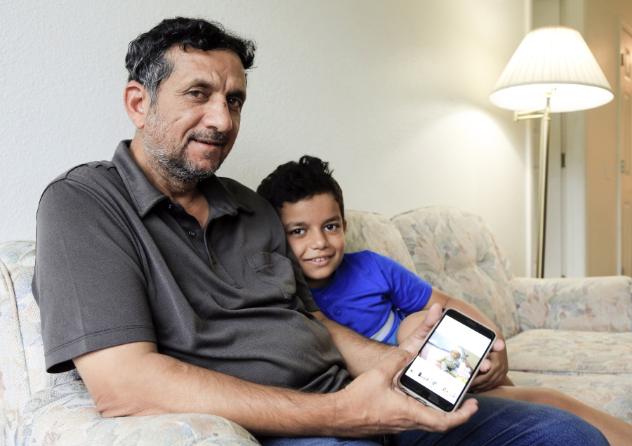 Hadi Mohammed sits Sept. 29 with his 9-year-old son Mohammed Ghaleb, as he displays a photo of his son as a baby in Baghdad, in their apartment in Lincoln, Neb. Death threats drove Mohammed out of Iraq to Nebraska, where he managed to settle as a refugee.