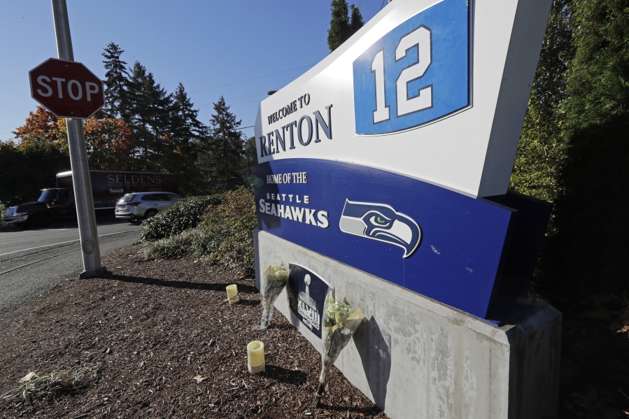 Flowers and candles rest near a sign for the Seattle Seahawks NFL football team headquarters Tuesday, Oct. 16, 2018, in Renton, Wash. in tribute to team owner Paul Allen, who died Monday, Oct. 15, 2018 in Seattle. (AP Photo/Ted S.