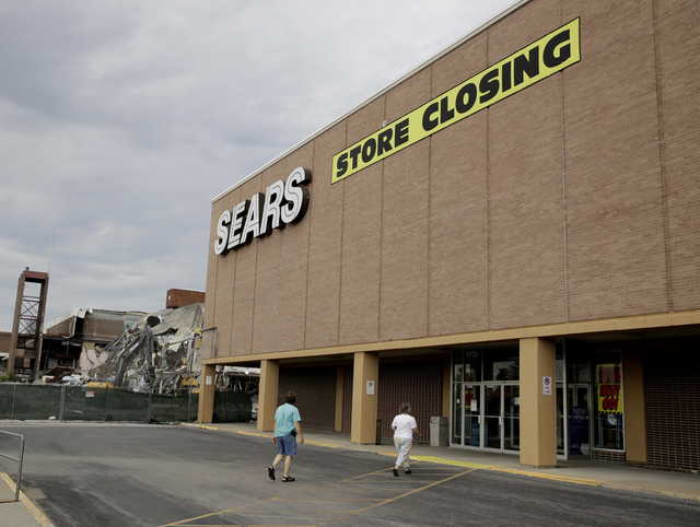 In this July 8, 2017, file photo people walk into a Sears store slated for closing that is next to a mall that is being torn down in Overland Park, Kan. Sears has filed for Chapter 11 bankruptcy protection Monday, Oct. 15, 2018, buckling under its massive debt load and staggering losses. The company once dominated the American landscape, but whether a smaller Sears can be viable remains in question.