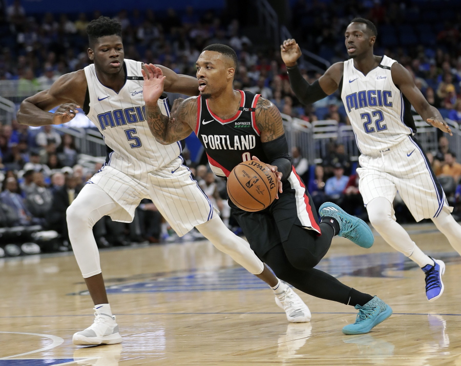 Portland Trail Blazers’ Damian Lillard, center, drives to the basket between Orlando Magic’s Jerian Grant (22) and Mohamed Bamba (5) during the second half of an NBA basketball game, Thursday, Oct. 25, 2018, in Orlando, Fla.