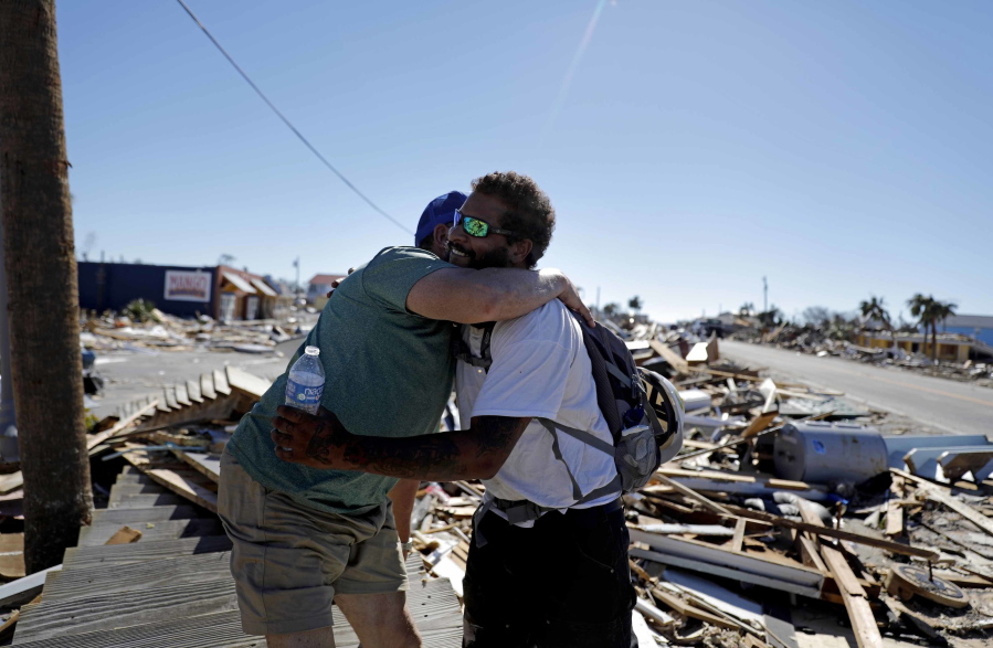 Hector Morales, left, is hugged by friend Matthew Goss, a fisherman, as they reunite after Hurricane Michael which destroyed Morales' home and Goss' boat in Mexico Beach, Fla., Friday, Oct. 12, 2018.