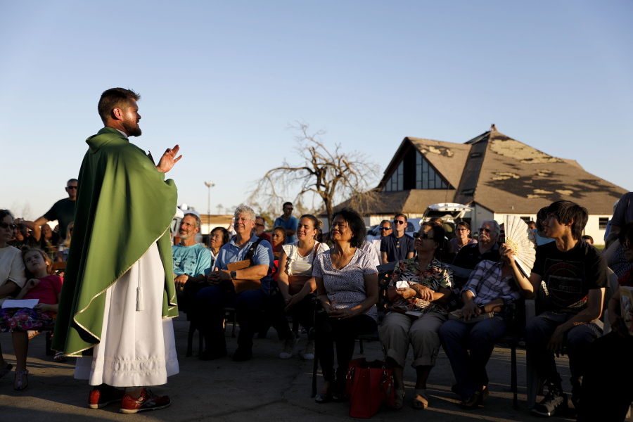Father Michael Nixon holds Mass on Saturday outside Saint Dominic Catholic Church, which stands damaged in the background, in Panama City, Fla.