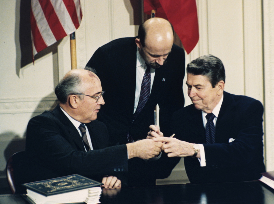 FILE - In this Dec. 8, 1987 file photo U.S. President Ronald Reagan, right, and Soviet leader Mikhail Gorbachev exchange pens during the Intermediate Range Nuclear Forces Treaty signing ceremony in the White House East Room in Washington, D.C. Gorbachev’s translator Pavel Palazhchenko stands in the middle. Trump’s announcement that the United States would leave the Intermediate-Range Nuclear Forces, or INF, treaty brought sharp criticism on Sunday Oct. 21, 2018, from Russian officials and from former Soviet President Mikhail Gorbachev, who signed the treaty in 1987 with President Ronald Reagan.