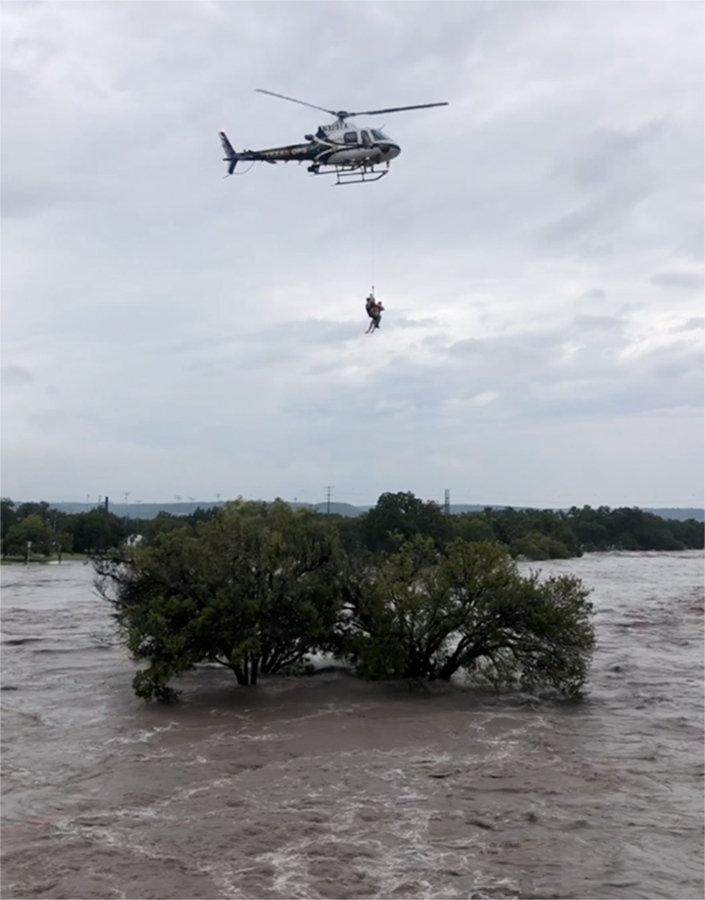A helicopter crew from the Texas Department of Public Safety performs a rescue Monday from the South Llano River near Junction, Texas. Rescue crews in boats and helicopters are searching for several people missing following heavy rain.