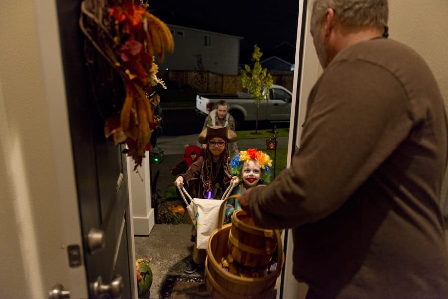 Liam Hooghkirk, 7, center, and Samual Hooghkirk, 4, in clown costume, trick-or-treat at Daniel Johnson’s house in the Hawks Landing development in Ridgefield in 2018. As the city continues to grow and more new developments pop up, it has spread out trick-or-treaters throughout the city.