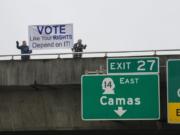 Vancouver residents Alan Pasternak, left, and Jim Walker encourage residents to vote while greeting motorists traveling south on Interstate 205 from the southeast 10th Street overpass Tuesday morning, Oct. 30, 2018.