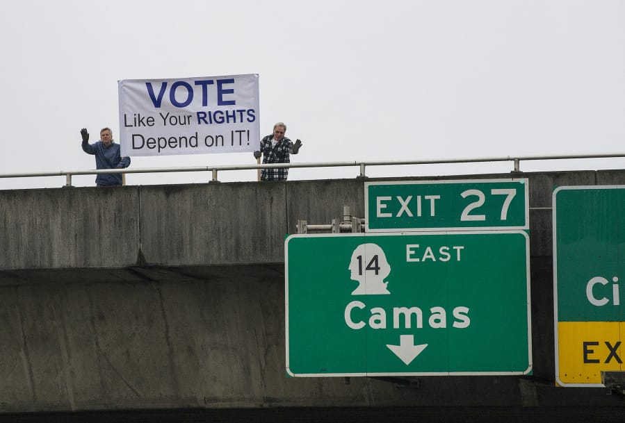 Vancouver residents Alan Pasternak, left, and Jim Walker encourage residents to vote while greeting motorists traveling south on Interstate 205 from the southeast 10th Street overpass Tuesday morning, Oct. 30, 2018.