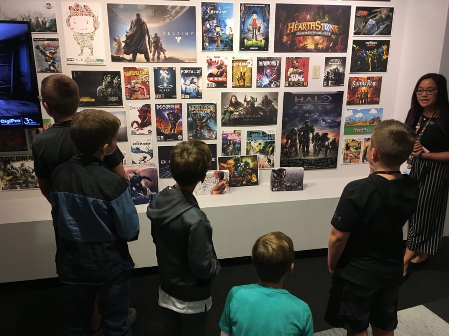Gamer League players, from left, Keaton Jaques, David Daley, Chad Grunwald, Grant Preisz and Cole Ulin view a wall of past video game cover art as part of a tour of DigiPen.